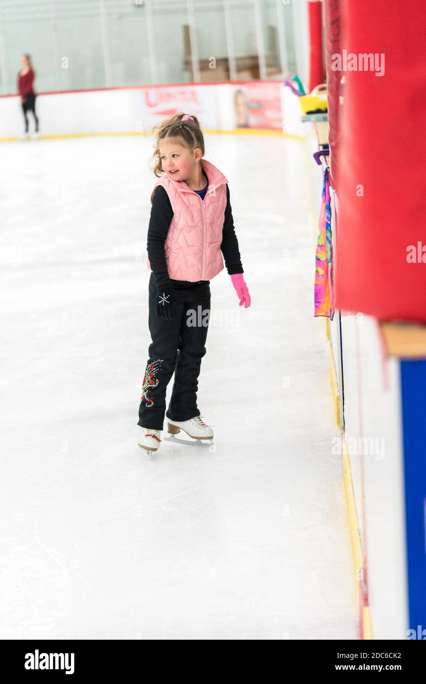 Little girl practicing figure skating elements on indoor ice skating