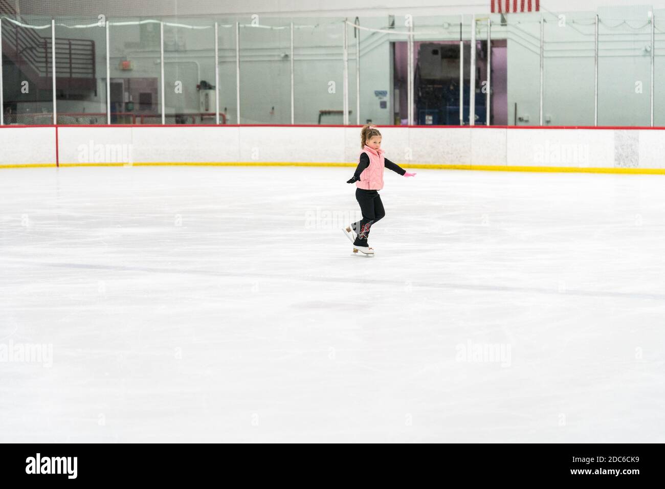Little girl practicing figure skating elements on indoor ice skating ...