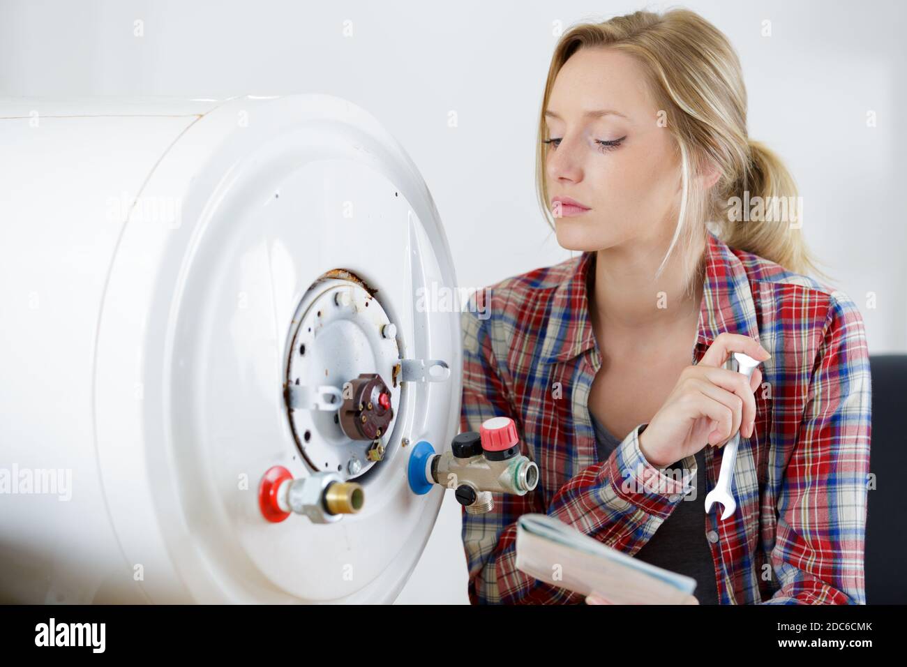 female trainee plumber working on central heating boiler Stock Photo