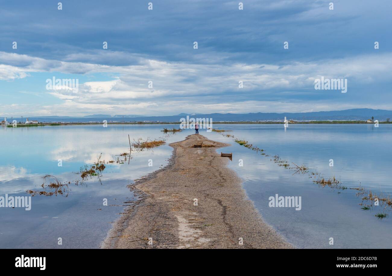 Flooded road under the cloudy sky and tourists taking selfie Stock Photo