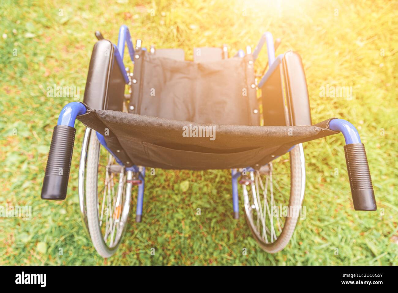 Empty wheelchair standing on grass in hospital park waiting for patient