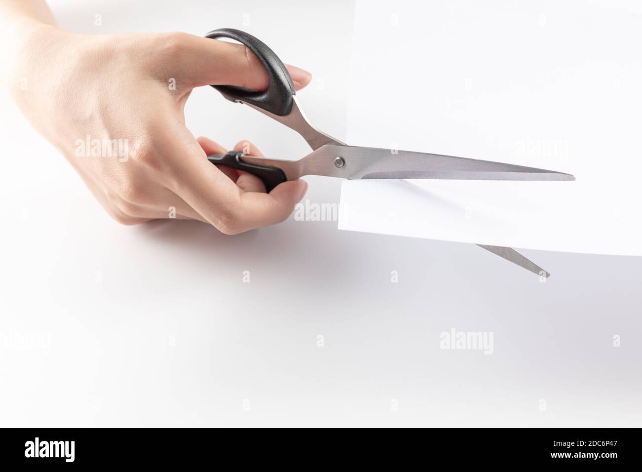 Close Up Of Hand Holding Scissors And Cutting Through Paper Stock