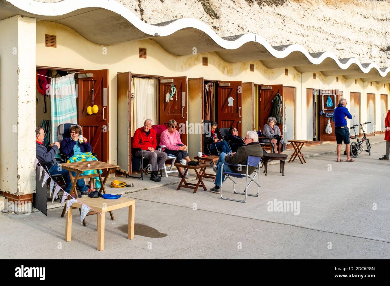 People Sittiing Outside Their Beach Huts During The Second Lockdown Of The Covid 19 Pandemic, Rottingdean, East Sussex, UK. Stock Photo