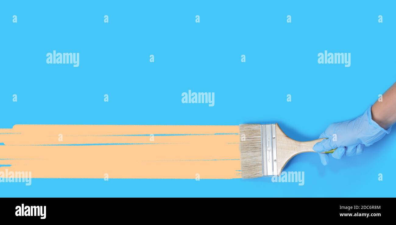 Brush for paint in hand on a blue background. Paint brush with wooden ...