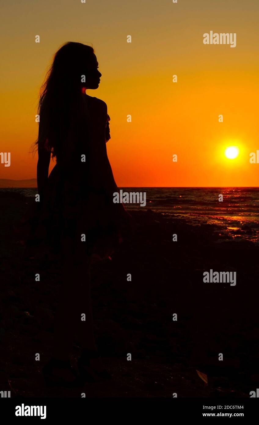 Silhouette of a young woman by the sea at sunset Stock Photo - Alamy