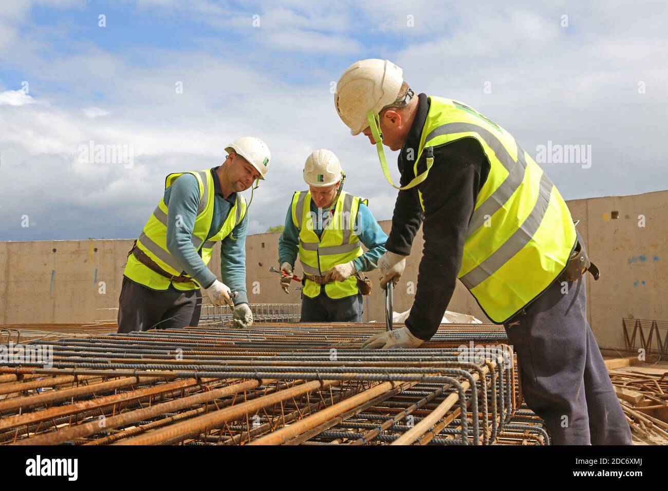 Three construction workers assemble a cage of steel reinforcement for insitu concrete on a large London building site Stock Photo