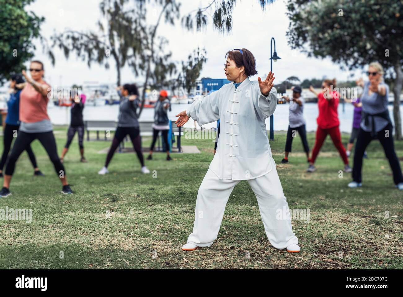 Mature chinese woman do tai chi with blirred group of people outdoor in the  park Stock Photo - Alamy