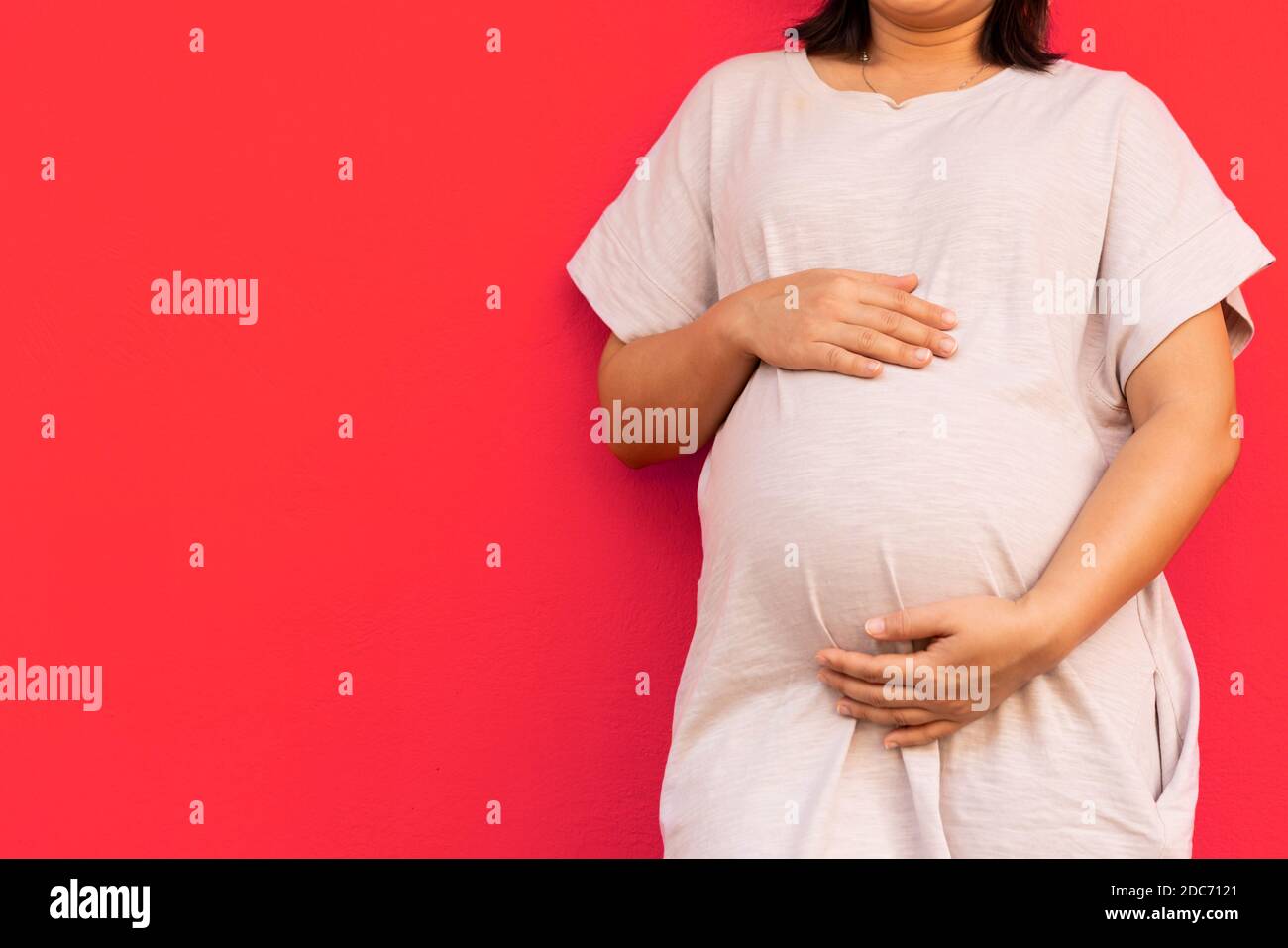 Pregnant woman feeling happy at home while taking care of her child. The young expecting mother holding baby in pregnant belly. Maternity prenatal Stock Photo