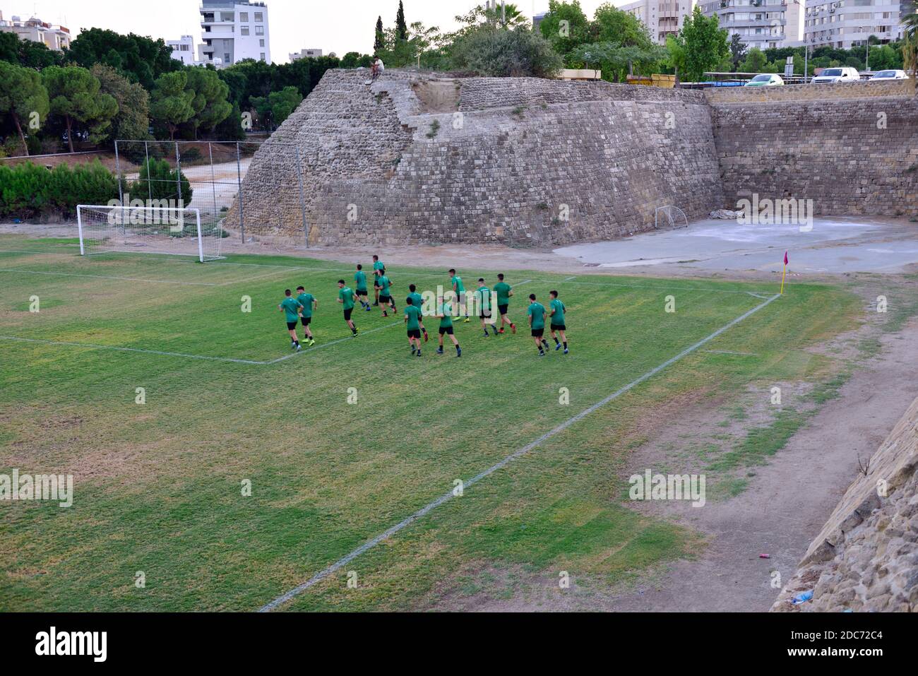 Amateur soccer team worming up in field under medieval Venetian wall surrounding older part of Nicosia, Greek Cyprus Stock Photo