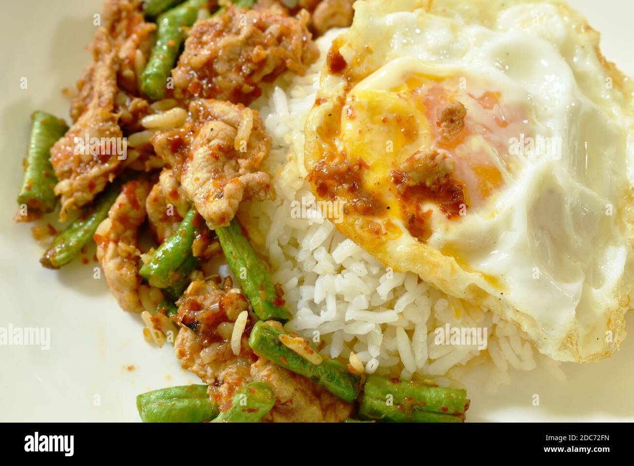 spicy stir fried pork with yard long bean curry topping egg on rice