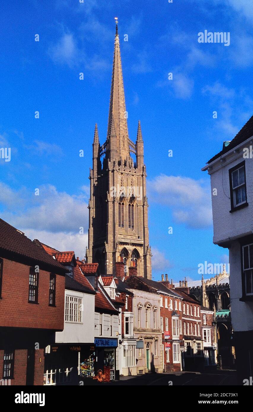 The tall spire of the Church of St. James behind the main street and shops. Louth. Lincolnshire. England. UK. Europe Stock Photo