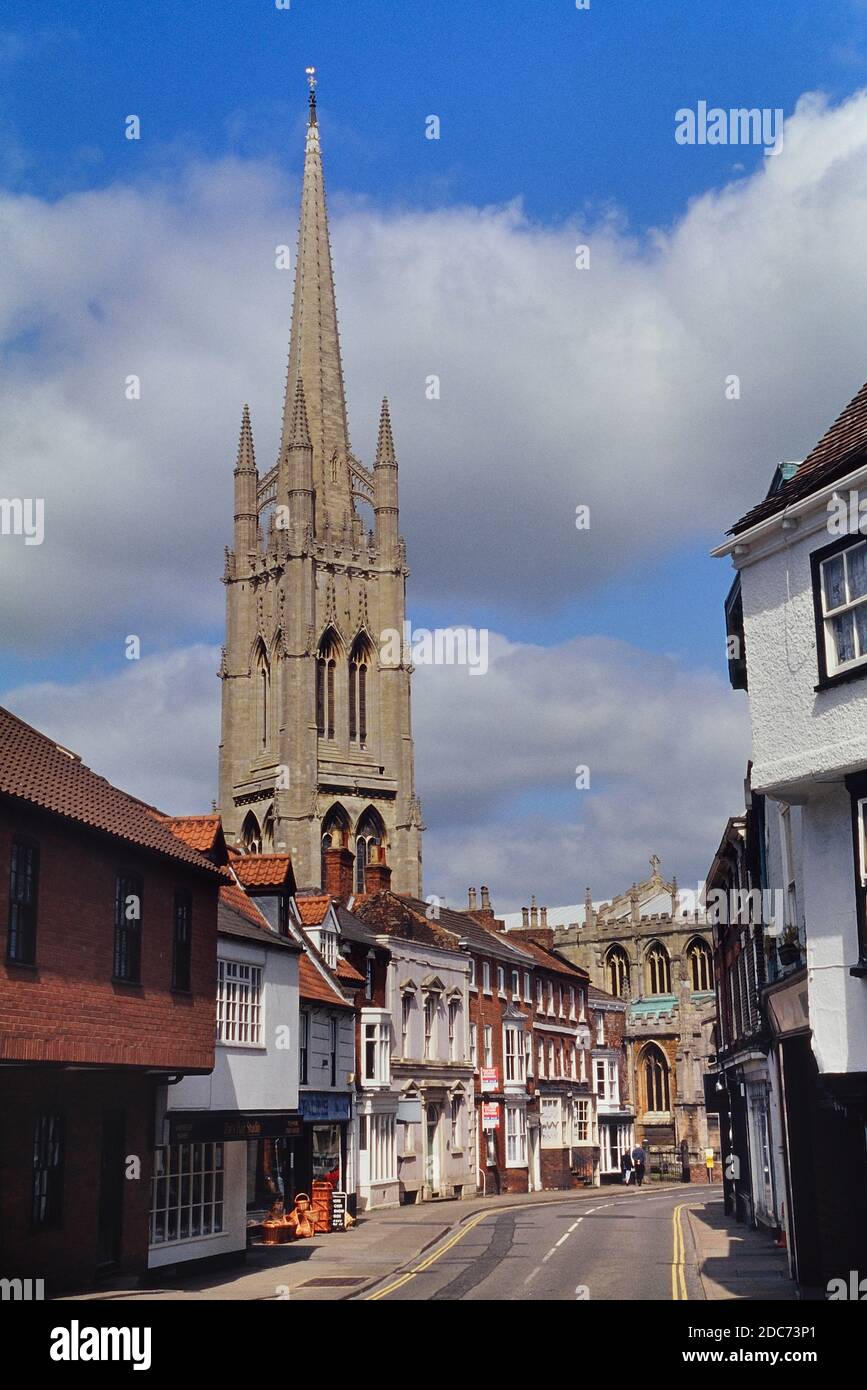The tall spire of the Church of St. James behind the main street and shops. Louth. Lincolnshire. England. UK. Europe Stock Photo
