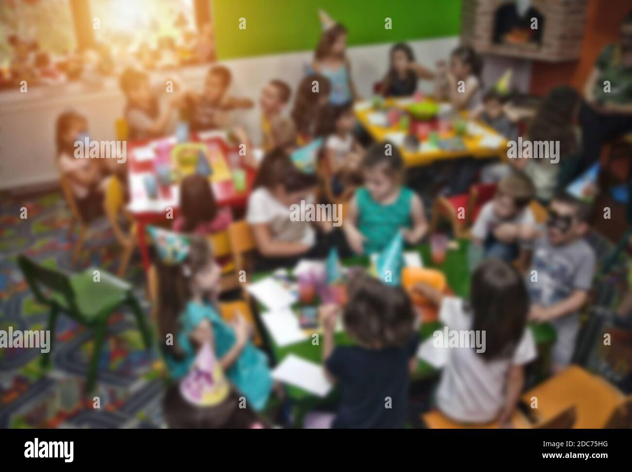 Blurred image for background usage. Kids at birthday party in a play room, sitting on little chairs. Stock Photo