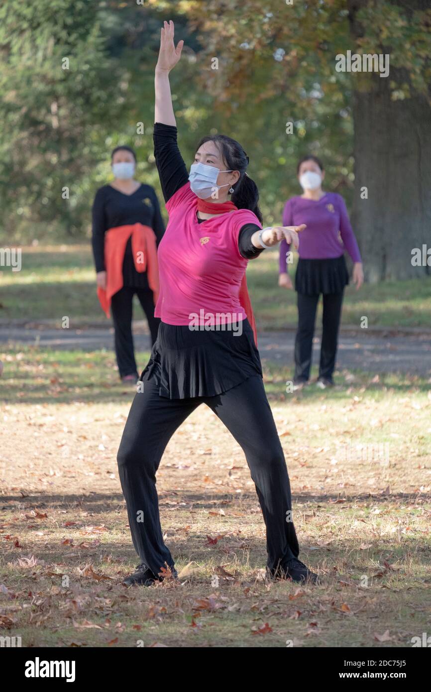 The teacher at an Asian American dance illustrates a position to her class in Kissena Park, Flushing, Queens, New York City. Stock Photo