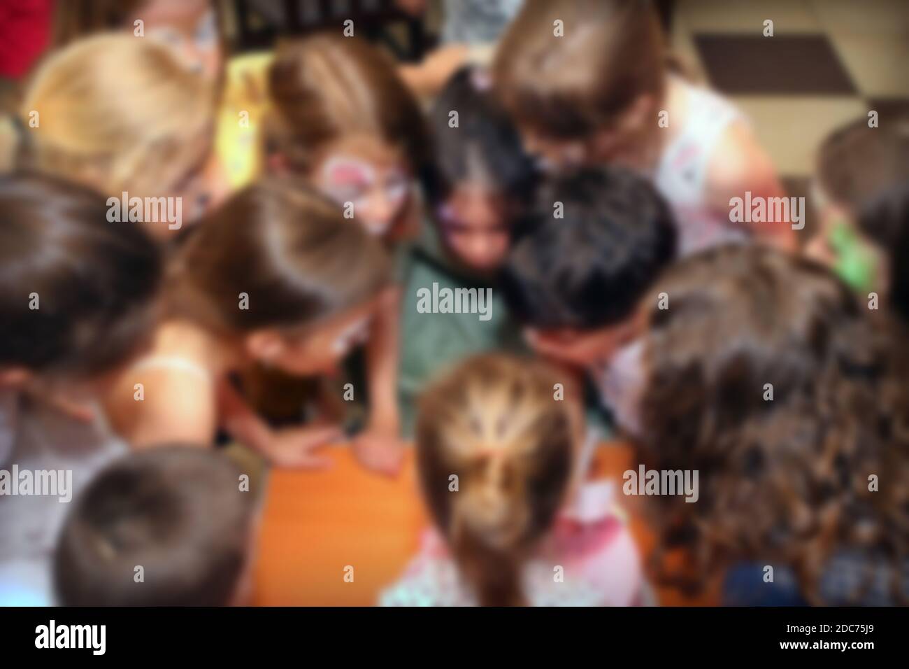 Kids gathered together and blowing candles at birthday party. Blurred image for background use. Stock Photo