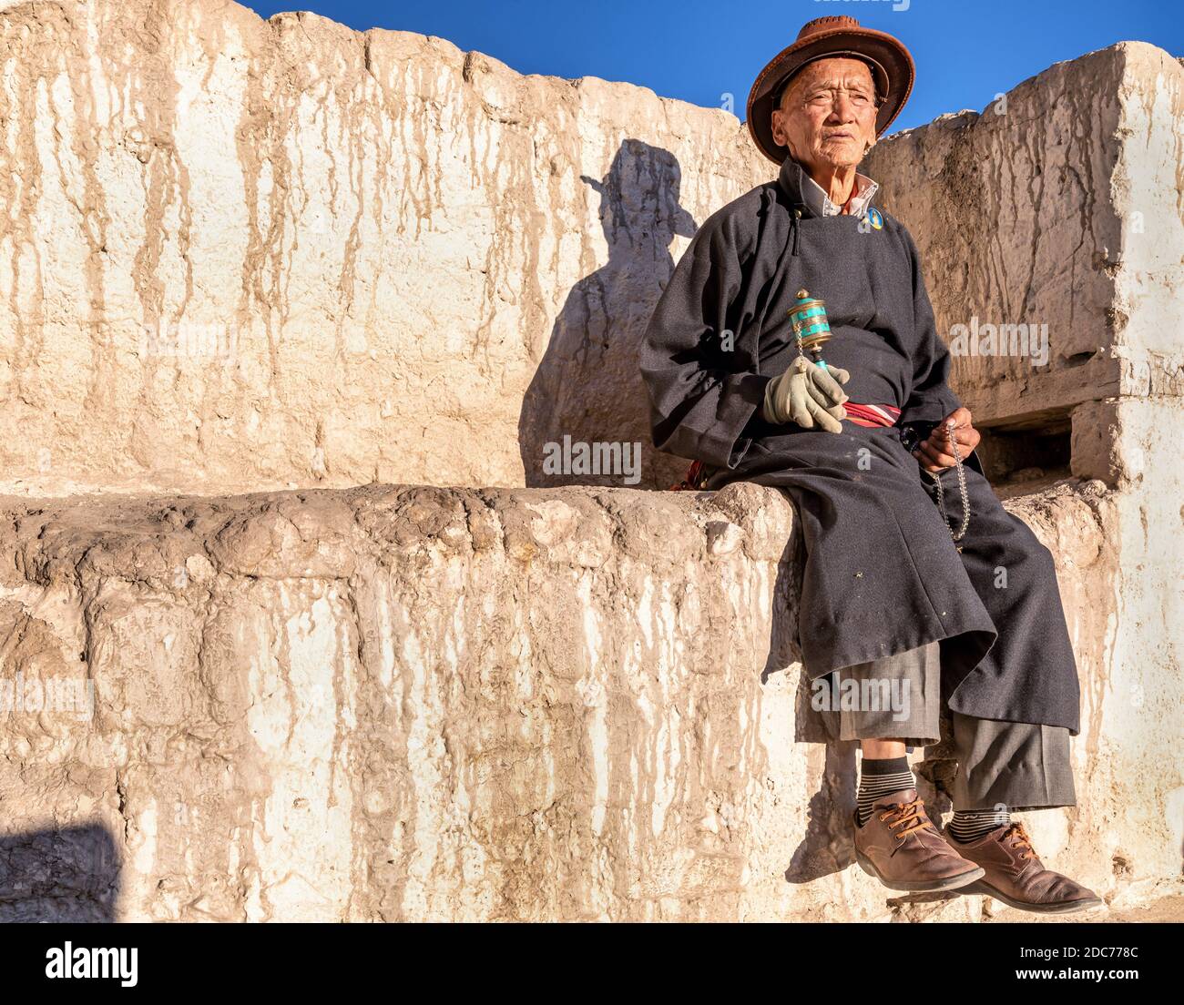 Elderly man with a prayer wheel resting at Spituk Gompa, Leh district, Ladakh, India Stock Photo