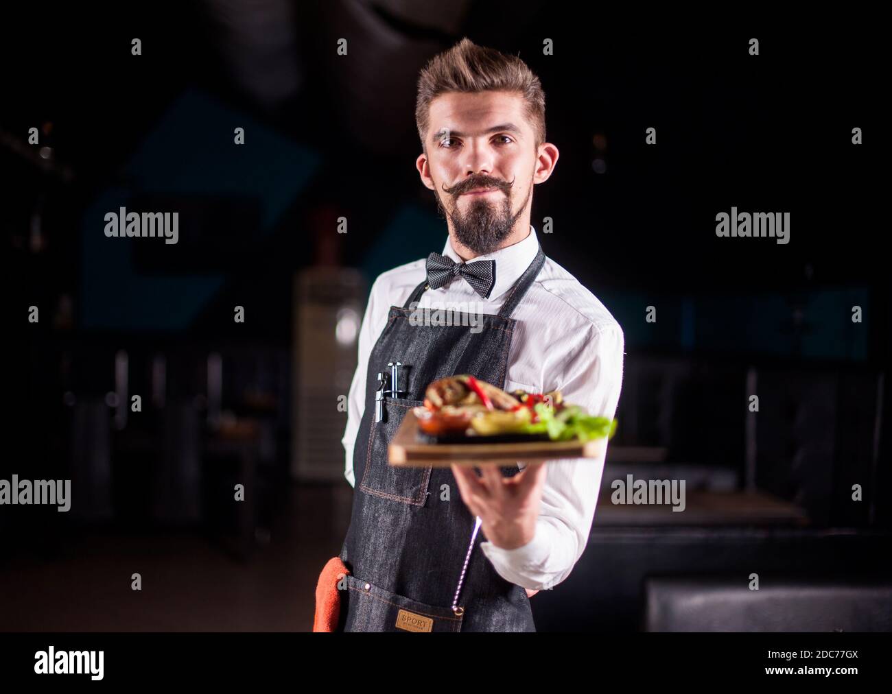 Helpful waiter helpfully serves appetizing dish in the restaurant. Stock Photo