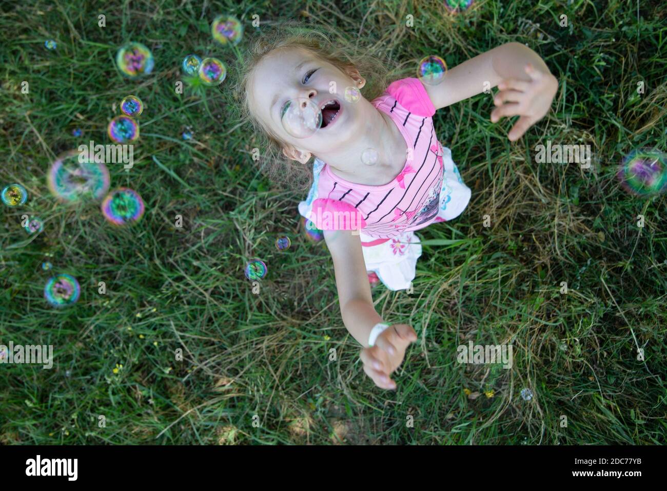Little blonde girl playing in the park with soap bubbles Stock Photo ...