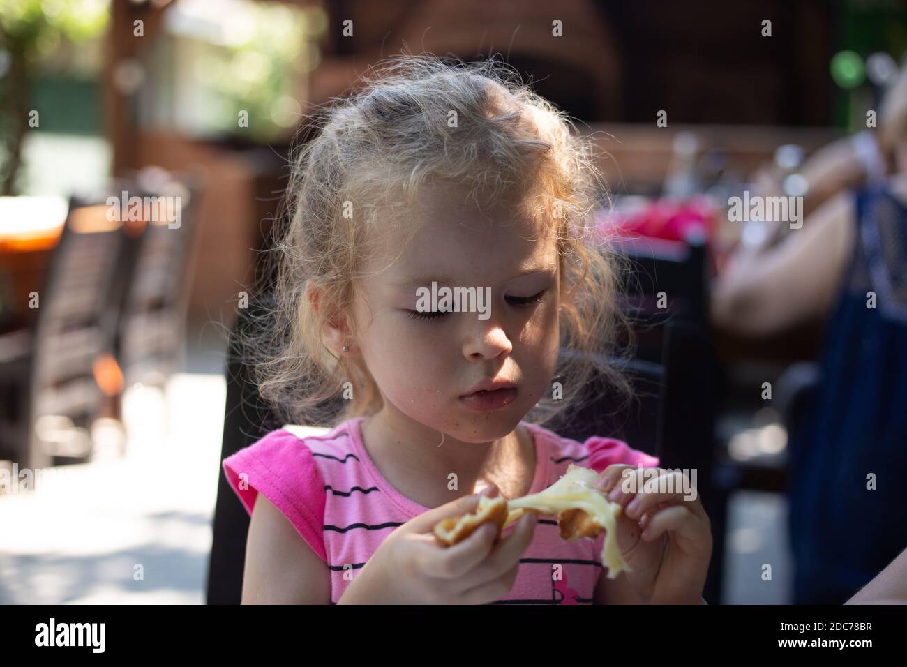 Little blonde girl eating at the restaurant Stock Photo