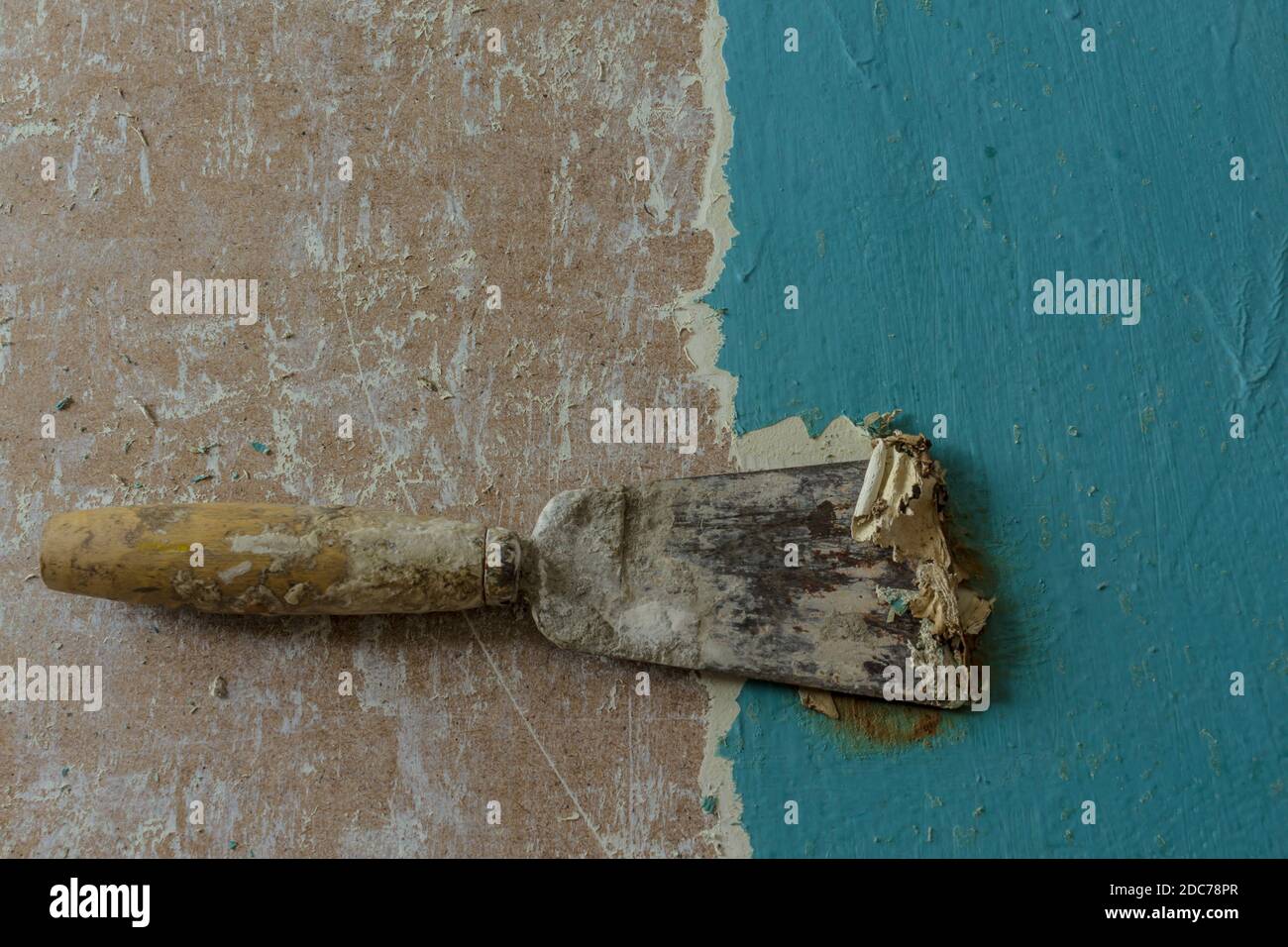 Restoration of an old door. Removing old paint coats with a heat gun and a spatula. View from above .The spatula removes the blue paint layer. Stock Photo