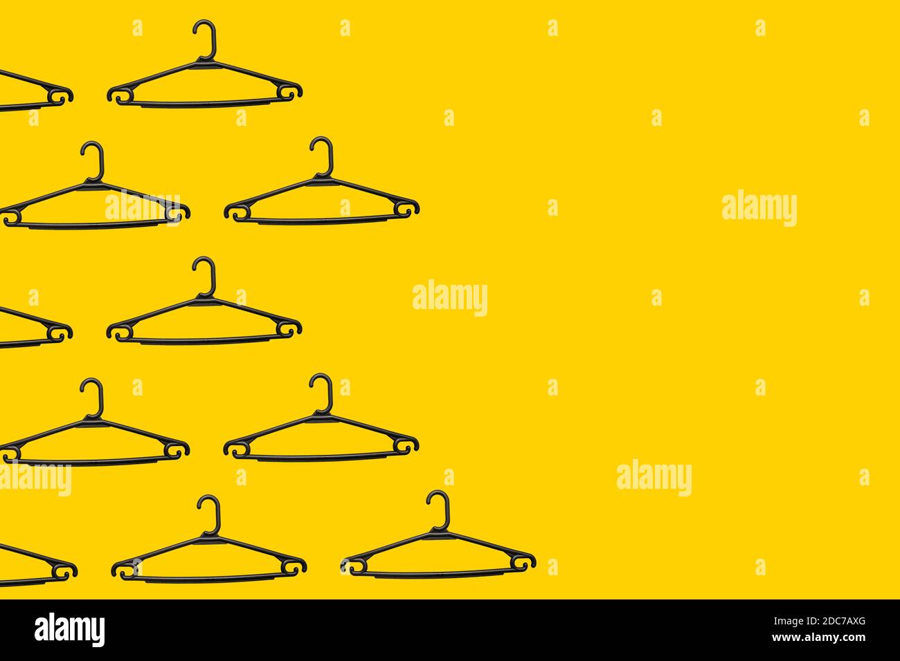 Pattern of black plastic hangers on a yellow background with copy space. The concept of selling goods, shopping and retail. Black Friday template. Stock Photo