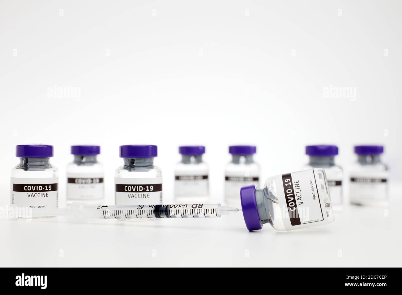 Closeup of vaccine phials for the treatment of coves-19 / coronavirus, pictured along with a syringe on white background Stock Photo
