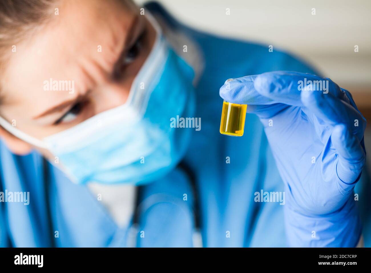 Medical worker inspecting ampoule vial bottle filled with yellow liquid,COVID-19 potential vaccine cure develop,convalescent patient platelet rich Stock Photo
