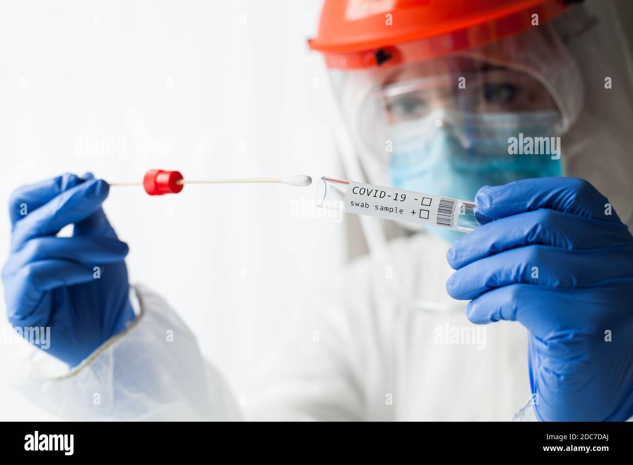Physician wearing personal protective equipment performing a Coronavirus COVID-19 PCR test, patient nasal NP and oral OP swab sample specimen Stock Photo