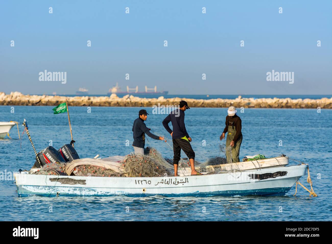 Three fishermen are fishing on a boat at the sea in Damman, Saudi