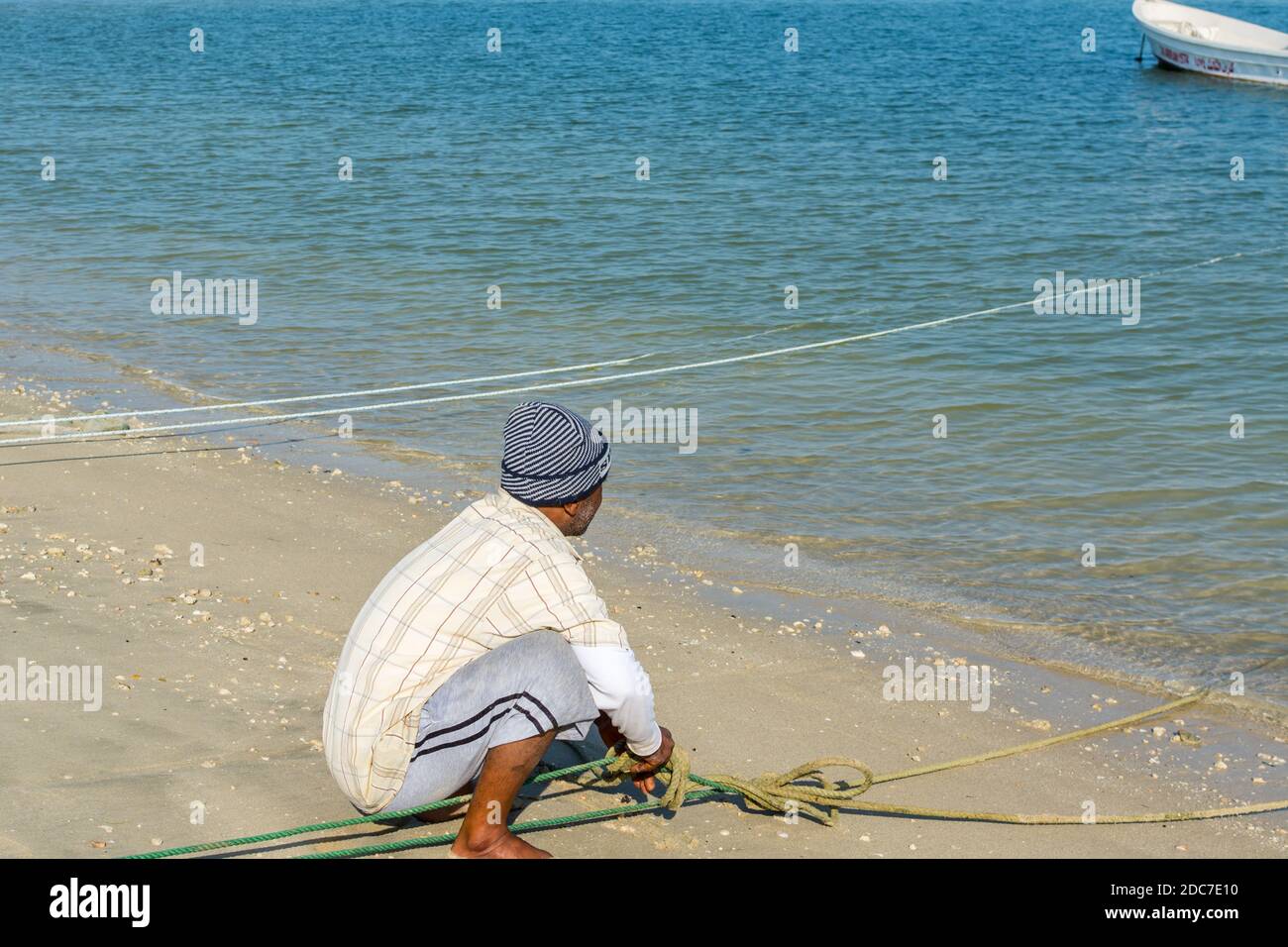 An Arabian fisherman tying yacht rope at the beach with background of ...