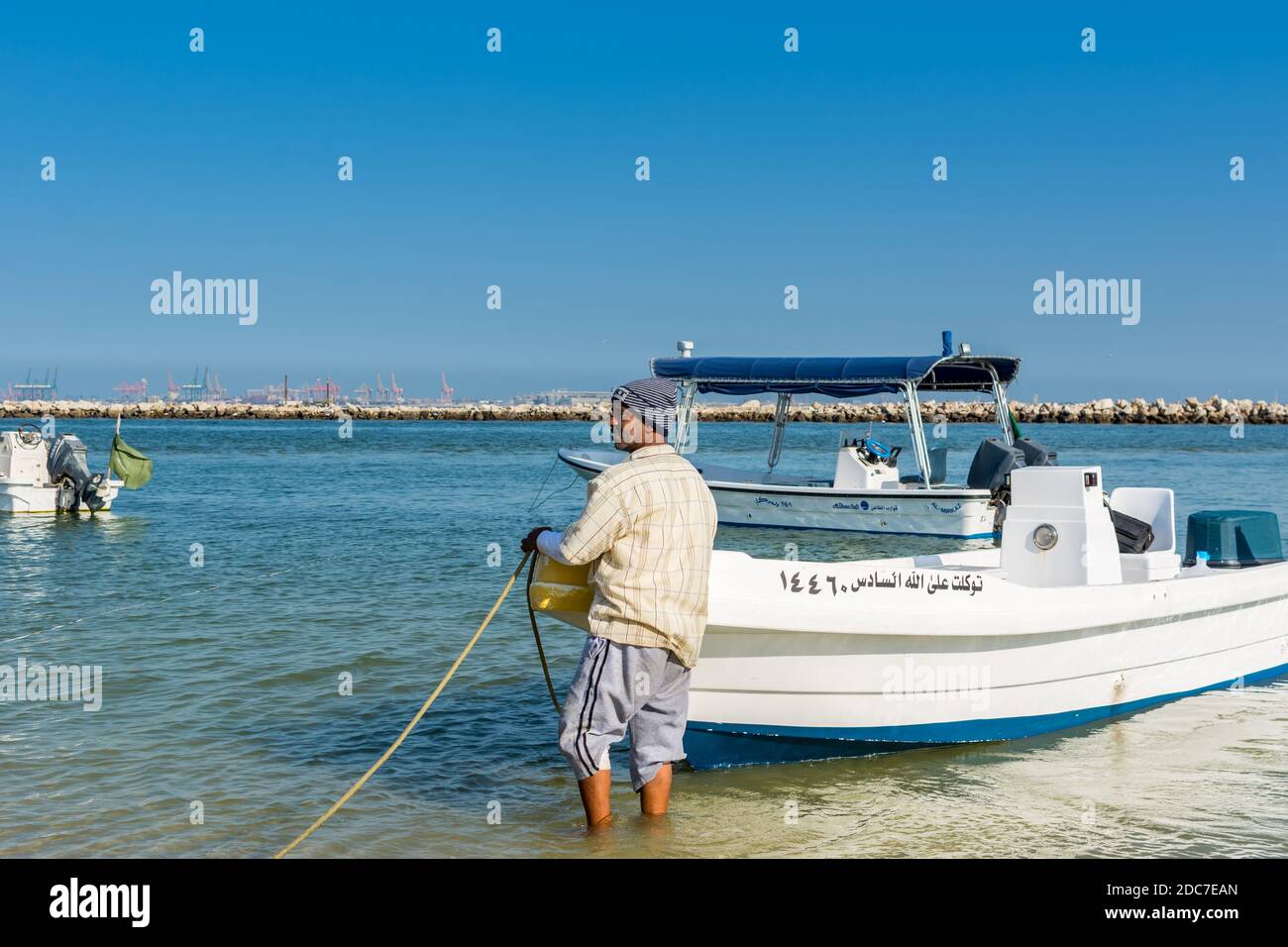 An Arabian fisherman tying yacht rope at the beach with background of ...