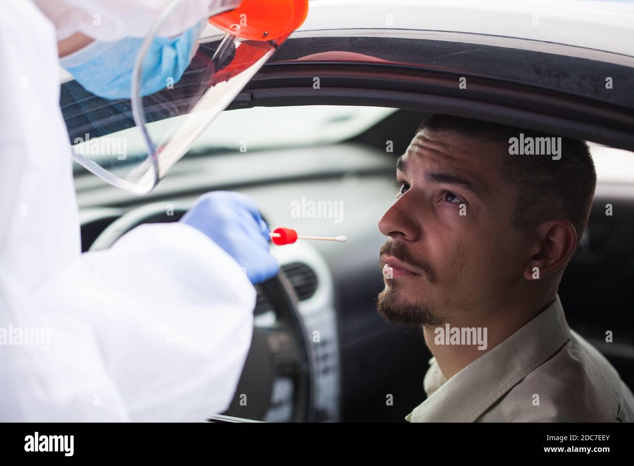 Young male in COVID-19 drive thru mobile testing center having nasal swab taken,Coronavirus testing procedure on a US site,swabbed specimen examined Stock Photo