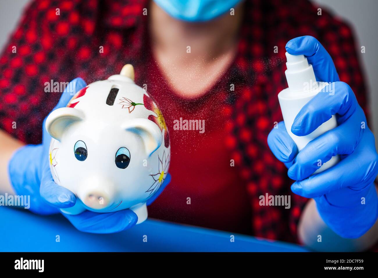 Coronavirus COVID-19 corona virus disease global pandemic outbreak,person holding piggy bank wearing blue surgical protective gloves,disinfecting Stock Photo