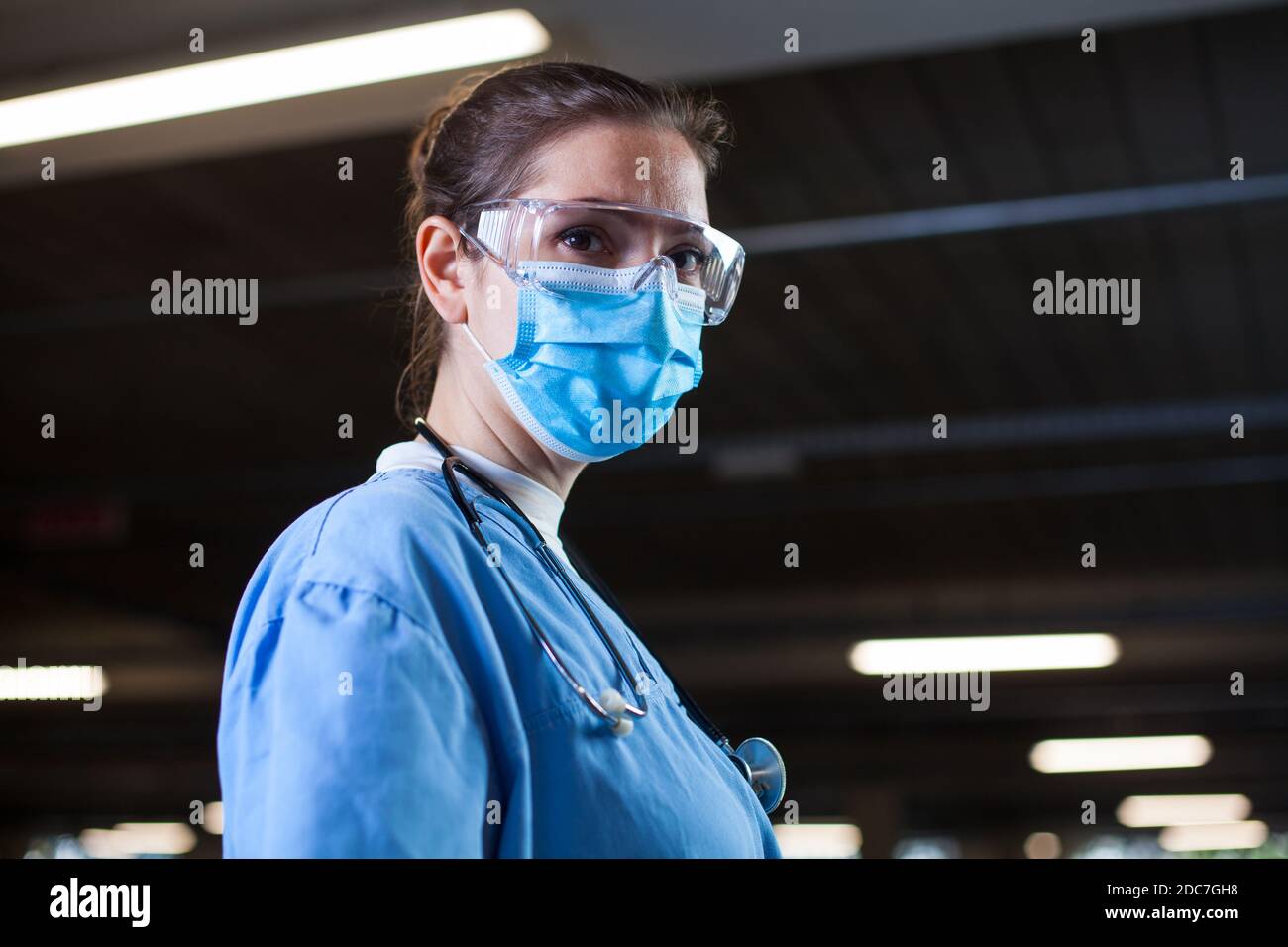 Young female UK NHS doctor in lab or hospital clinic,worried and anxious,tired and exhausted after long shifts,Coronavirus COVID-19 pandemic crisis ca Stock Photo