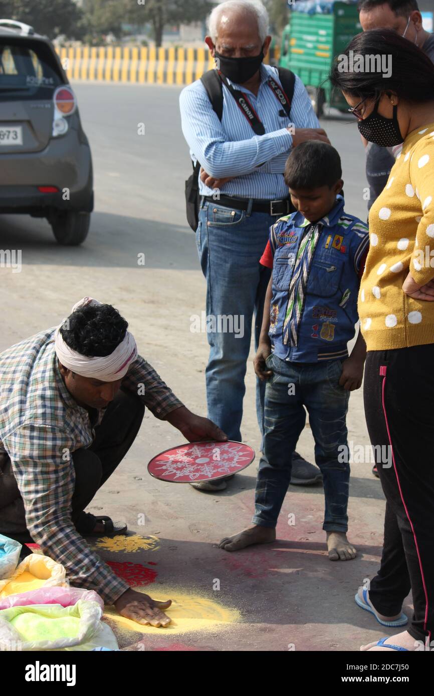 In this shot artisan is demonstrating on road, Rangoli art by using a ...