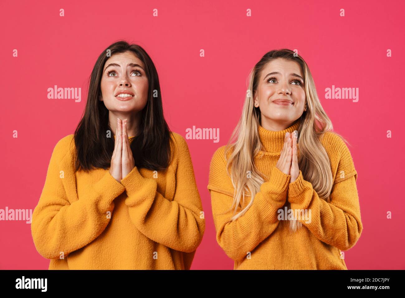 Image of unhappy caucasian women holding palms together and looking upward isolated over pink background Stock Photo