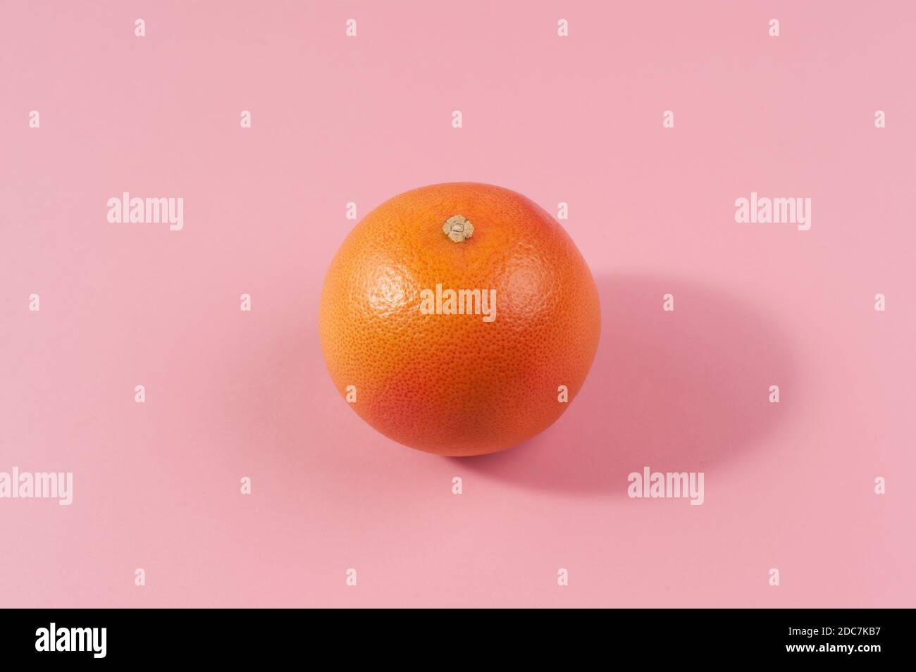 Creative background made with grapefruit citrus fruit  and shadow on the bright  pink background. Minimal image  concept. Stock Photo