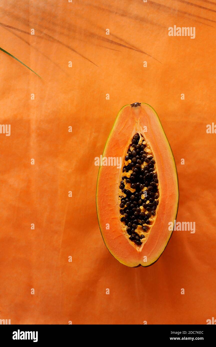 Creative background with Papaya  and  leaf on the background.  Food background. Vertical orientation with space for text. Stock Photo