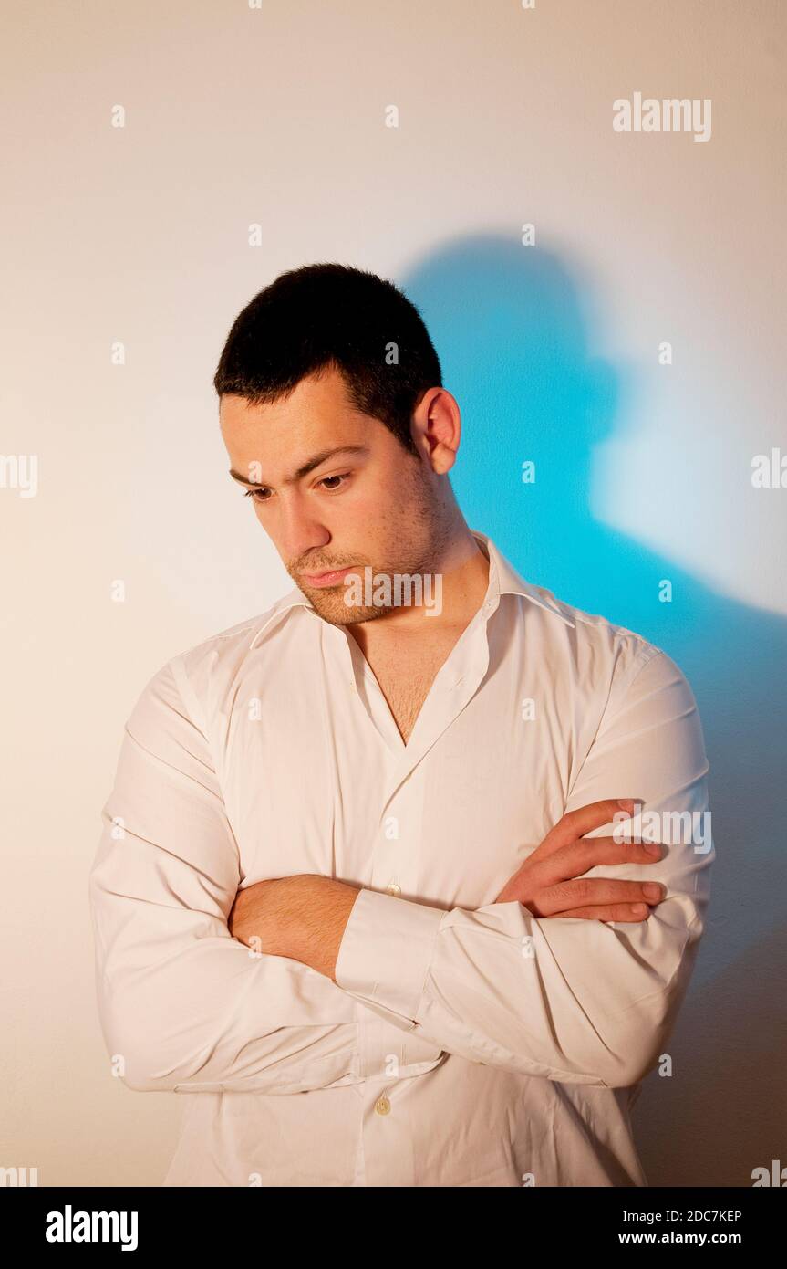 Young man,crossing arms, looking down. Stock Photo