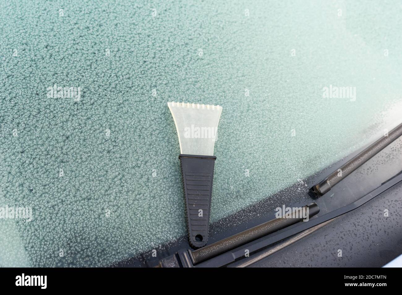 frosted car glass. Frosty patterns on a car windscreen . scraper for