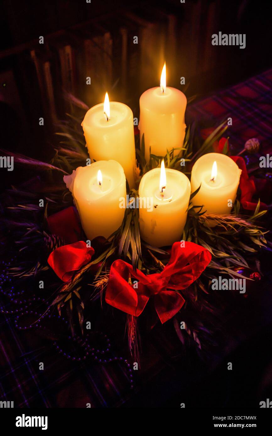 Advent candles, with all five candles lit on Christmas Eve, surrounded
