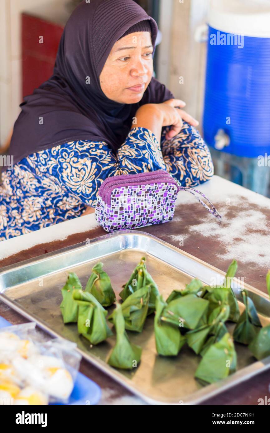 A muslim woman selling traditional Thai rice cakes wrapped in banana leaves in Phuket, Thailand Stock Photo