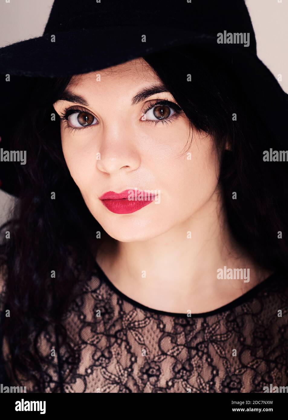 Beautiful young woma with big eyes wearing a black hat and red lipstick Stock Photo