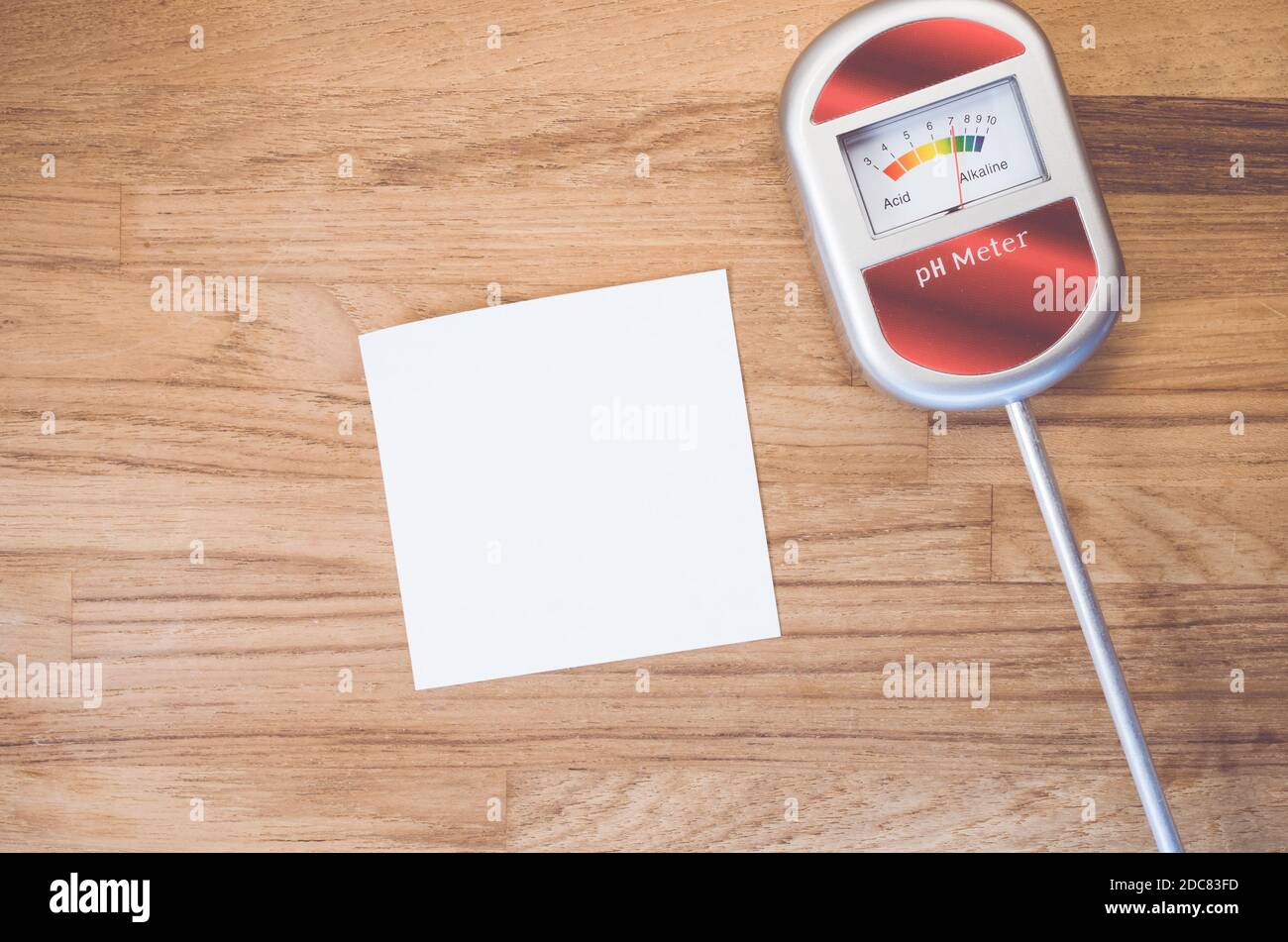 A closeup shot of a PH measurement tool and papers on a wooden table Stock Photo