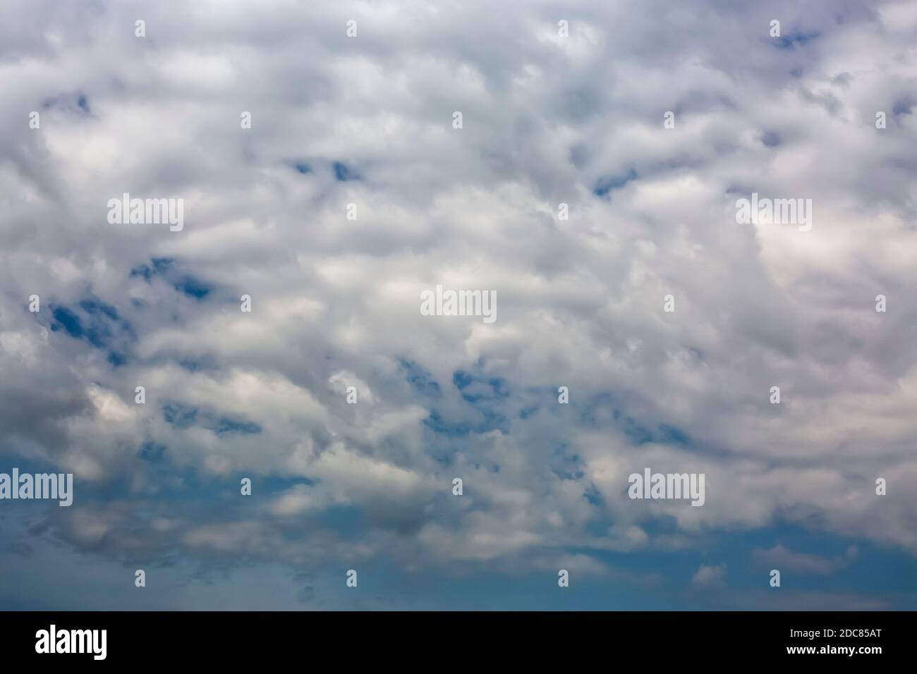 Cloudscape with white clouds against clear blue sky Stock Photo - Alamy