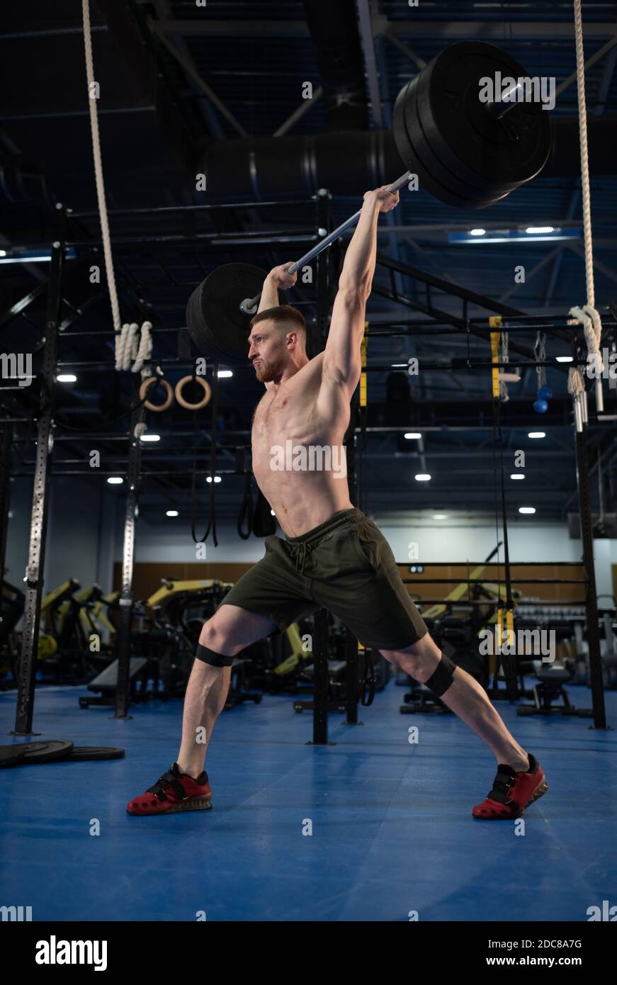 Strong weightlifter lifting barbell over head while doing clean and