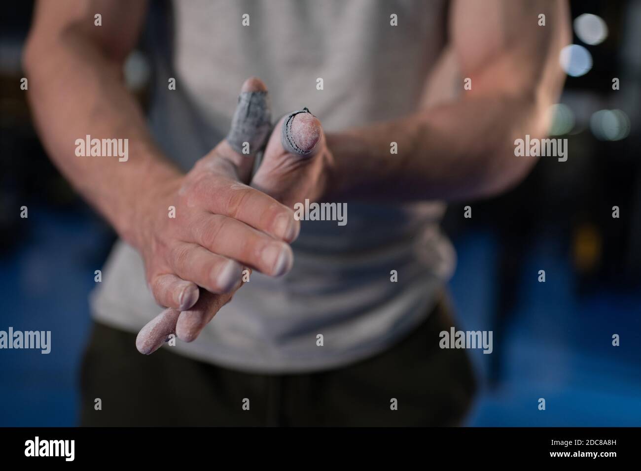 Anonymous sportsman spreading chalk on hands during weightlifting
