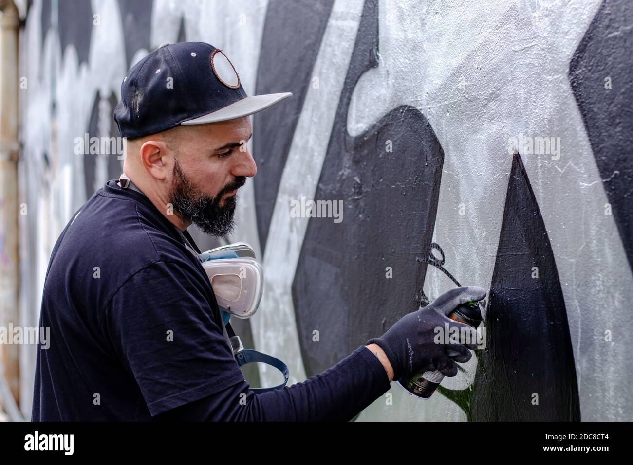 Graffiti artist in action, painting on the wall with aerosol spray ...