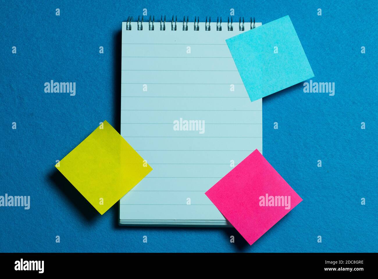 blank page of notebook and colorful post it on light blue background Stock Photo