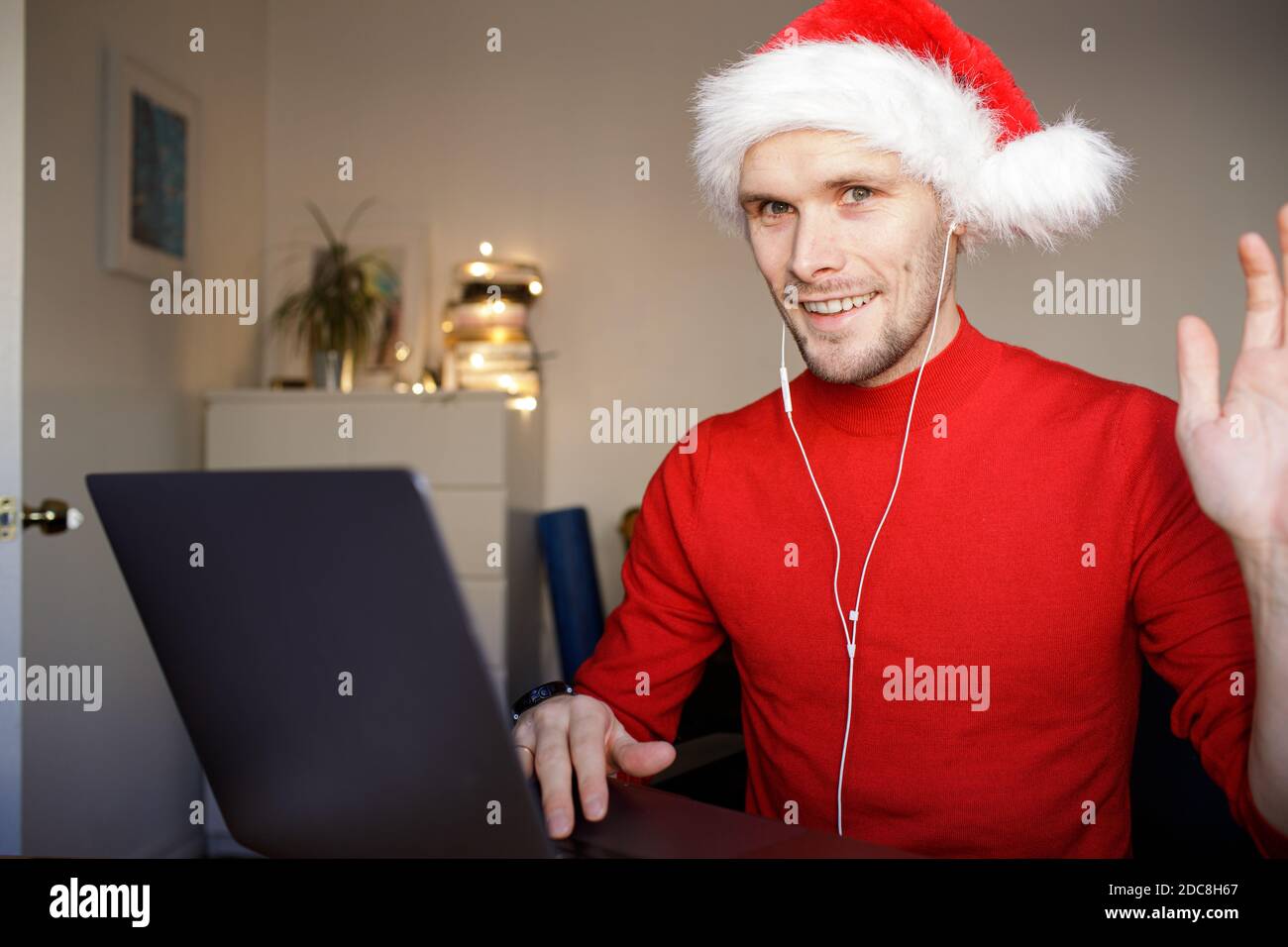 A video call on Christmas computer in the home office. Man wearing Santa hat. Business video conferencing. Virtual thanksgiving house party. Online Stock Photo